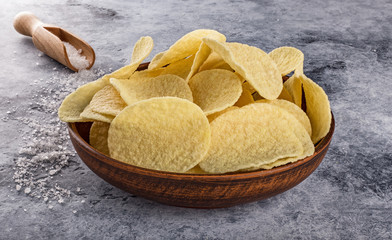 Potato chips on grey concrete table. Concept of fast food and snacks.