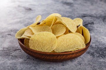 Potato chips on grey concrete table. Concept of fast food and snacks.