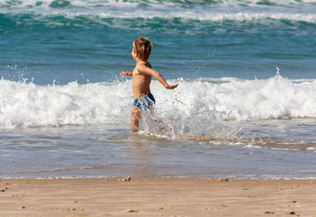 Fototapeta premium the child runs into the sea spraying water