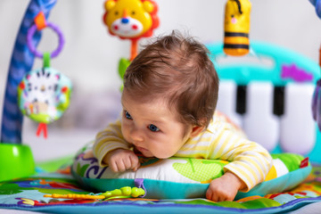 Fototapeta na wymiar Neugeborenes Baby mit bunten Spielsachen liegt auf den Bauch