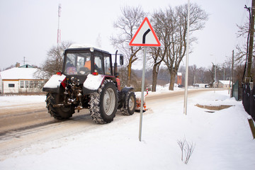 Fototapeta premium red tractor clears the road from snow