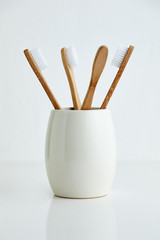 Four bamboo toothbrushes in gray glass