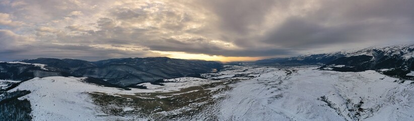 Aerial view of a gold sunset over winter snow.Panorama.