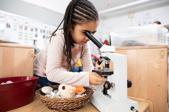 Girl using microscope in classroom