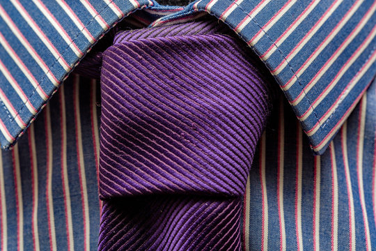Close up of business pinstripe shirt and purple necktie tied with a double windsor knot