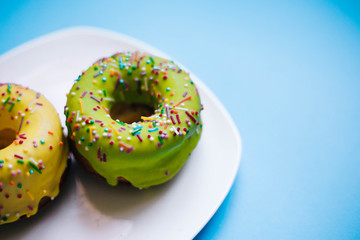 Two color donuts. Yellow and Green Donut on a blue background. Dessert