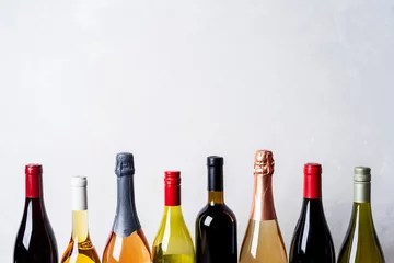 Schilderijen op glas Tops van verschillende soorten nieuwe flessen champagne, witte, rode wijn op lichte achtergrond © PINKASEVICH