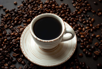 Coffee cup with roasted beans on stone background 