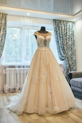 Fototapeta na wymiar beautiful wedding dress hanging in the room, woman getting ready before ceremony