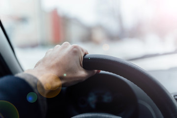 driving a car on a sunny day. driver's hand on the steering wheel.