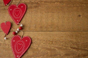 Three red hearts on a wooden background.