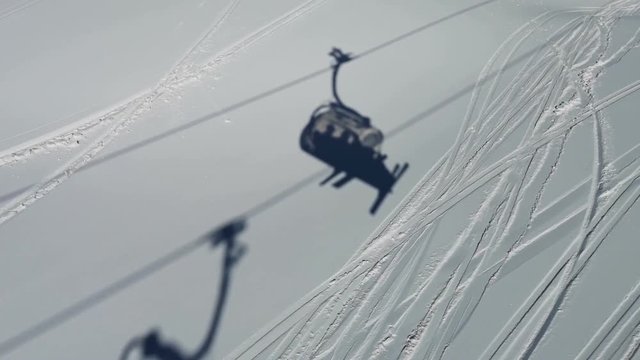 Clip with skiers going up in a chair lift. Silhouette of the cable car is seen on the ski resort slopes.