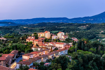 Fototapeta na wymiar Chiusi village cityscape at night before sunrise in Umbria Italy with illuminated lights and rooftop houses on mountain countryside and rolling hills