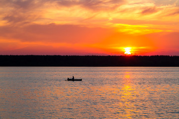 Fototapeta premium Fishermen float on a lake at sunset