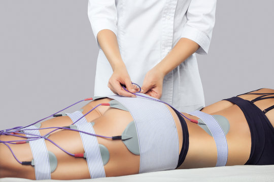 The procedure of myostimulation on the legs and buttocks of a woman in a beauty salon. Caring for the body, reducing excess weight.