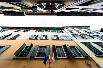Firenze, Italy Old building street architecture alley facade in Florence, Tuscany during morning with nobody yellow orange color and flags