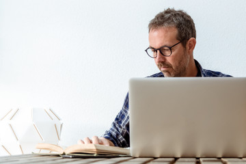 Business man computer student studying doing research using technology books professional sending mail middle-aged working from home while reading book writer engaged in writing novel Frontal portrait