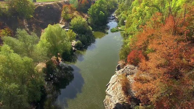 aerial view of autumn canyon, mountain river in canyon, flying over buky canyon in the autumn, big stones in the autumn river, waterfall in autumn colors with big stones