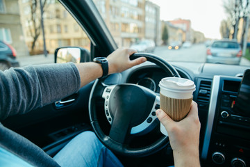 man hands holding steering wheel and cup of coffee. morning booster