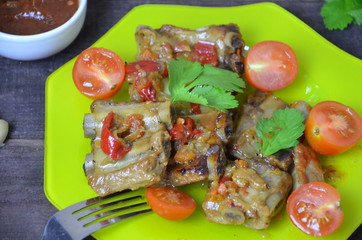 Pork ribs braised with soy sauce and vegetable tomato on the plate.