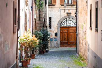 Orvieto, Italy Italian outdoor empty street and building door in Umbria historic city town village cobblestone road typical narrow alley with decorations plants garden