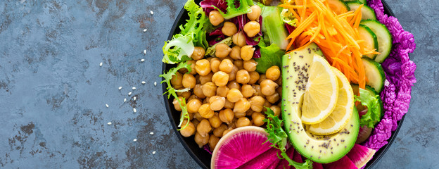 Salad Buddha bowl with fresh cucumber, avocado, watermelon radish, raw carrot, lettuce and chickpea for lunch. Healthy vegetarian food. Vegan vegetable dish. Top view. Banner