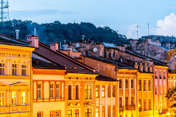 Historic Lviv, Ukraine cityscape exterior with yellow architecture buildings in old town market square in evening night illuminated multicolor houses
