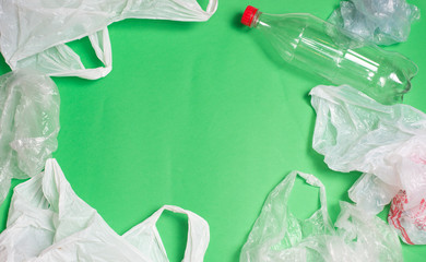 plastic bags and bottles on a green background with space for text..ecology mockup