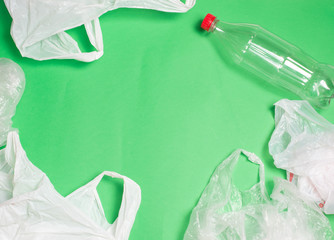 plastic bags and bottles on a green background with space for text..ecology mockup