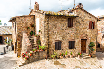 Monticchiello, Italy Val D'Orcia countryside in Tuscany with empty street in small town village with nobody and plants on typical stone house