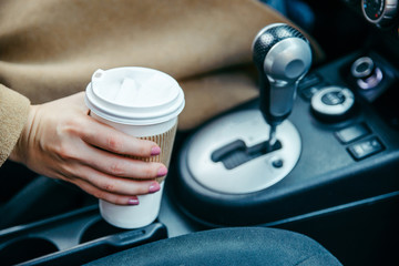 woman hand taking cup with coffee in car. close up. crop