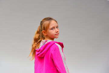 Portrait of a girl in a pink sweater on a gray background in the studio.