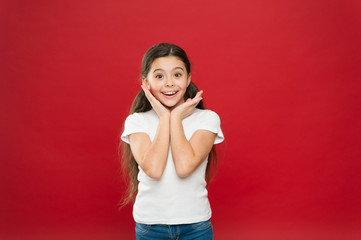 Little girl excited smiling face. Kid happy cute face feels excited red background. Exciting moments. Excitement emotion. Sincere excitement. Kid girl long healthy shiny hair wear casual clothes