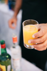 Closeup shot of a barman's hand serving a yellow drink