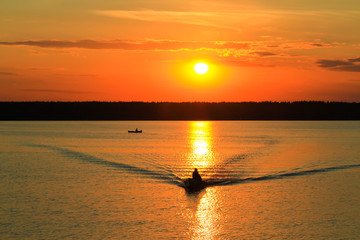 Fishermen float on a lake at sunset