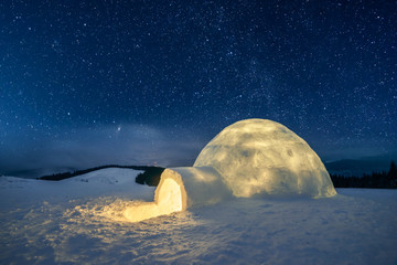 Fantastic winter landscape glowing by star light. Wintry scene with snowy igloo and milky way in night sky - obrazy, fototapety, plakaty