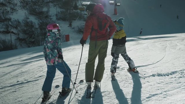 A young family adjusting their skiing gear at the bottom of the slopes at the Dolomites ski mountains in Belluno, Italy.