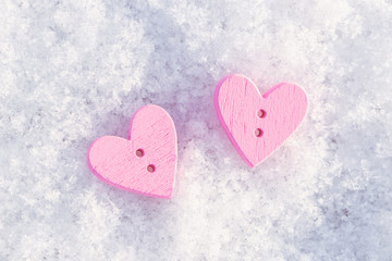 Two pink wooden hearts on white snow. View from above. Background to the Valentine's day and wedding.