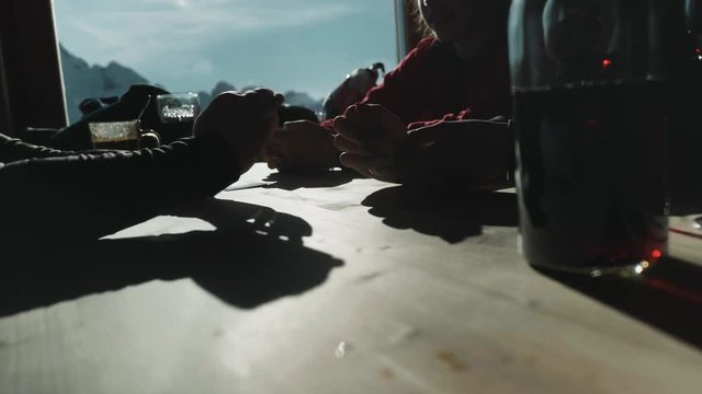 A young family plays cards in a ski lodge, taking a break from skiing down the hills.