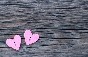 Two pink hearts in the corner of the image on a wooden surface. Background to the Valentine's day and wedding.