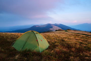 Green tent in spring mountains. Amazing evening highland. Landscape photography