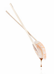 Drop of soy sauce drips from a fresh sushi roll with shrimp, isolated on a white background