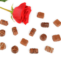 Assortment of chocolates and red rose isolated on white background.