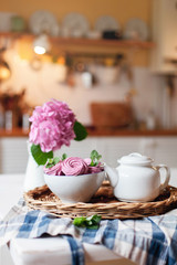 Obraz na płótnie Canvas Pink marshmallows, white teapot and hydrangea flowers are serving on straw tray. Morning breakfast on kitchen table. Tea time, home atmosphere hygge. Cozy still life with sweets.