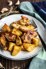 Baked chicken wings with potatoes and garlic on a rustic background