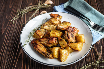 Baked chicken wings with potatoes and garlic on a rustic background