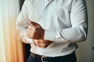 Fototapeta premium businessman dresses white shirt, male hands closeup,groom getting ready in the morning before wedding ceremony. Men Fashion