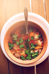 Clay plate with ear soup with a spoon on the table in a cafe