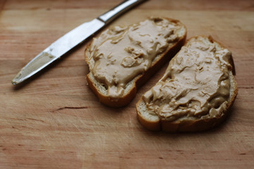 Homemade peanut butter sandwiches or toasts and knife on old wooden background