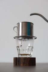Traditional Vietnamese filtered coffee. Pouring hot water into phin minimalist style